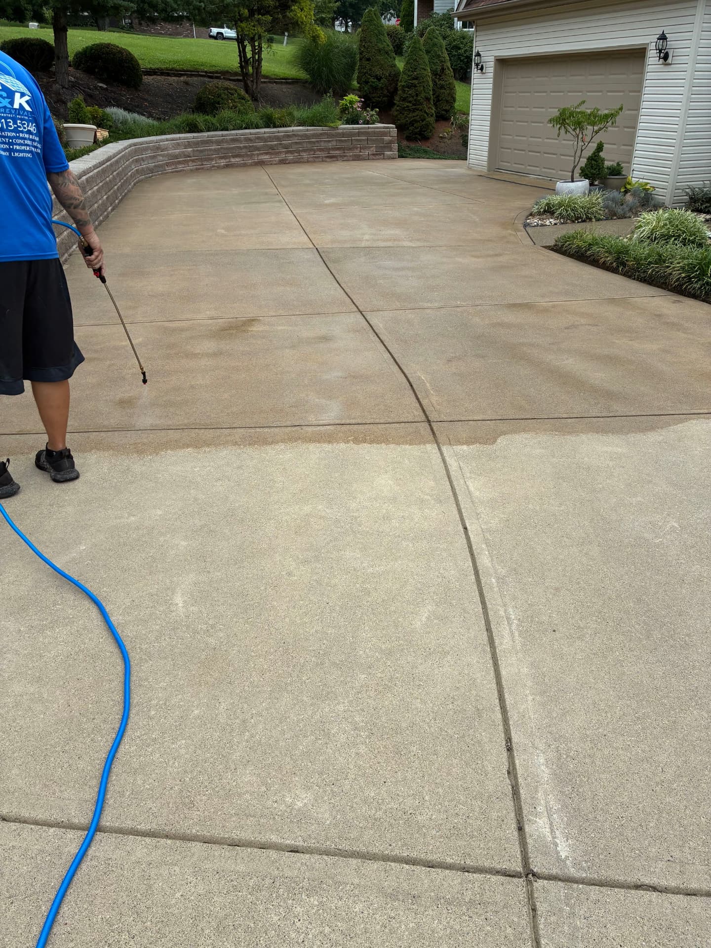 H&K Roof Revival technician cleaning a residential concrete driveway